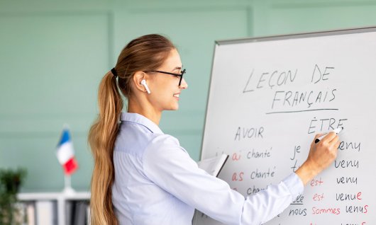 Lehrerin steht vor einem Whiteboard und unterrichtet französisch. 