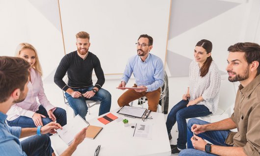 Erwachsene sitzen um einen Tisch und unterhalten sich