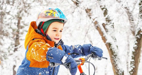 Ein Kind fährt Fahrrad im Schnee.