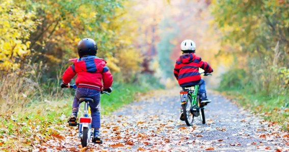 Zwei Kinder fahren am winterlichen Waldweg Rad