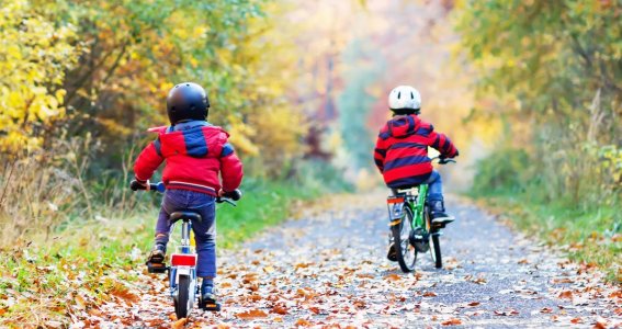 Zwei Kinder fahren am winterlichen Waldweg Rad