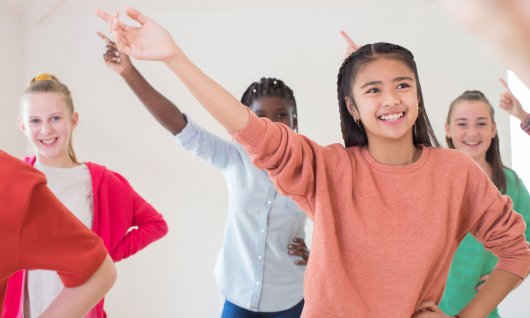 Englischsprachkurse für Kinder in Düsseldorf Kinder stehen im Raum und halten Arme in die Luft.