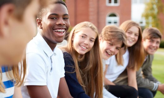 Englischsprachkurse für Kinder in Düsseldorf Jugendliche sitzen nebeneinander und lachen.