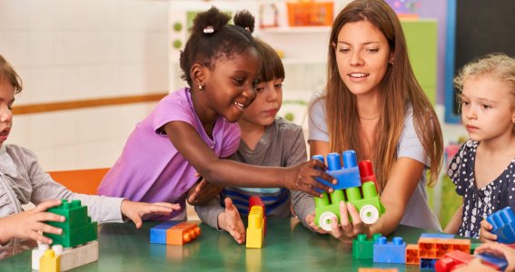 Kinder spielen mit einer Frau zusammen Spiele am Tisch. 