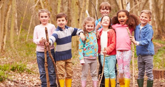 Kinder stehen im Wald und lachen in die Kamera 