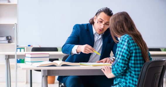 Lehrer und Mädchen sitzen am Tisch und lernen 