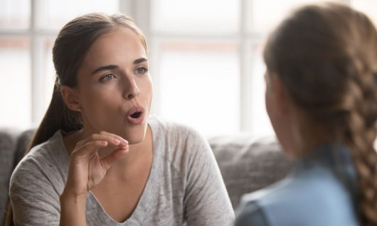 Sprachkurse für Kinder Frau bringt einem Mädchen die Aussprache bei