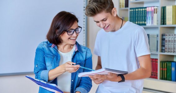 Junge und Frau stehen nebeneinander und schauen in ein Buch