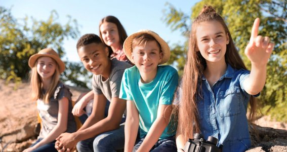 Kinder sitzen auf einem Stein mit Fernglas