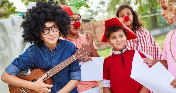 Kinder stehen mit Gitarre und Kostümen im Garten