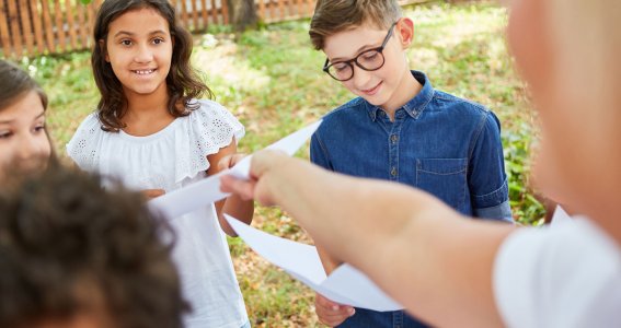 Kinder stehen mit Blättern im Garten