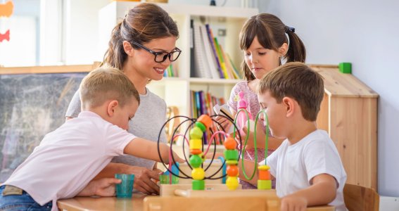 Kinder spielen am Tisch mit einer Frau