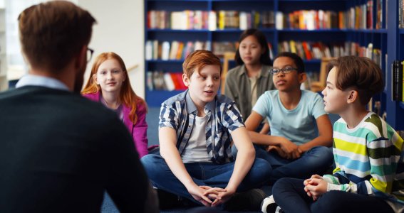 Jugendliche sitzen in einem Raum mit Büchern