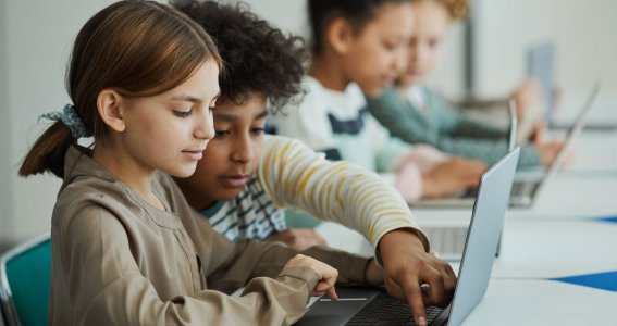 Vier Kinder sitzen vor Laptops 