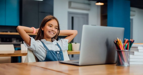 Mädchen sitzt glücklich vor Laptop