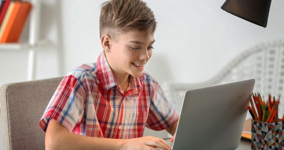 Junge sitzt vor einem Laptop