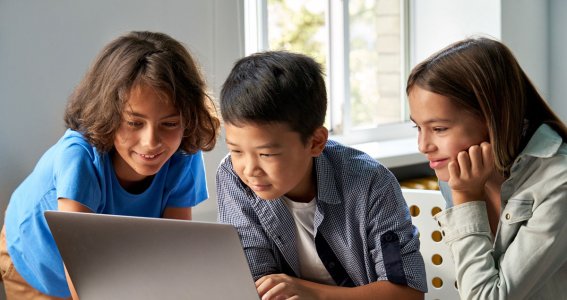 Drei Kinder schauen auf einen Laptop