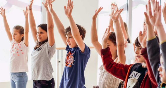 Kinder heben beim Tanzen die Arme hoch 