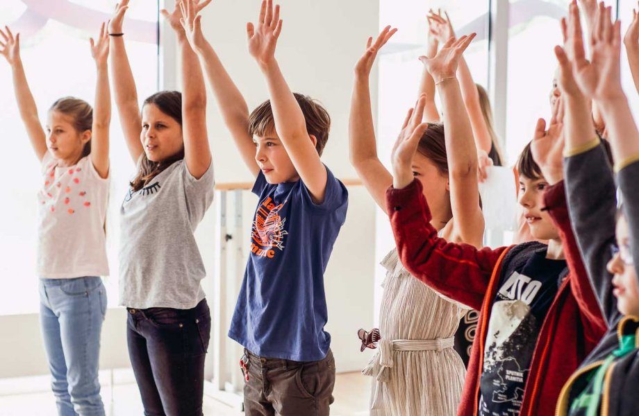 Kinder heben beim Tanzen die Arme hoch 