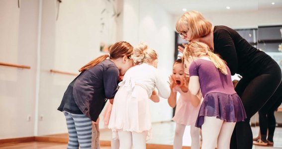 Ballettlehrerin und Tänzerinnen stehen im Kreis