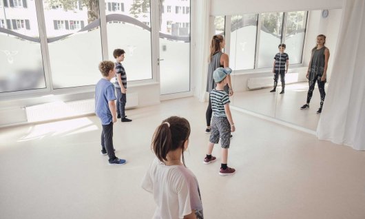 Trainerin und Kinder stehen vor dem Spiegel