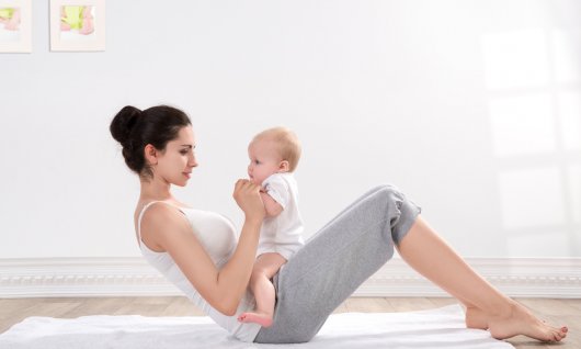 Frau macht Übungen mit ihrem Baby