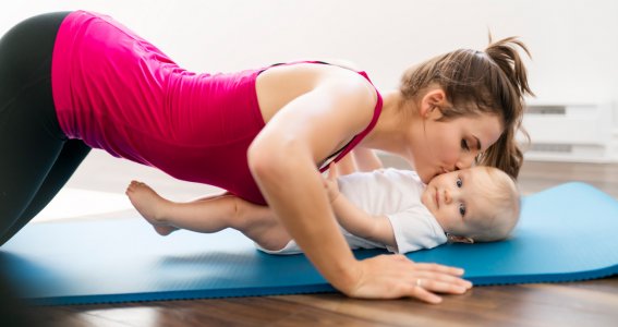 Mama macht eine Übung und küsst ihr Baby