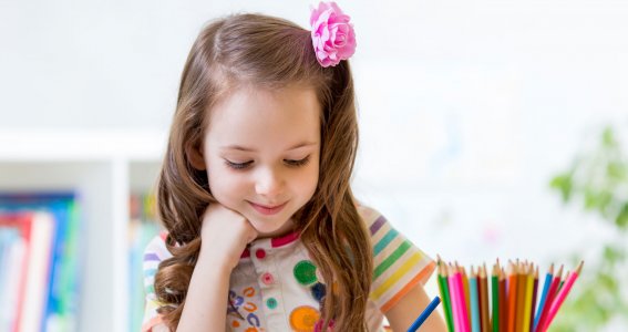 Kleines Mädchen malt ein Bild mit Buntstiften.