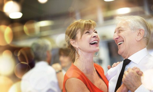 Ein lachendes Seniorenpaar tanzt Gesellschaftstanz