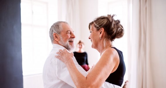 Ein Seniorenpaar tanzt in einem hellen Raum