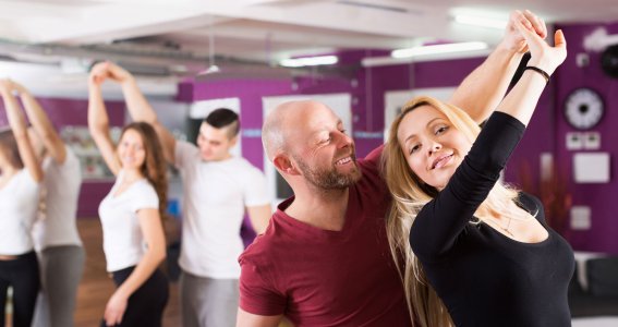 Zwei junge Paare tanzen in einem Raum mit Spiegelwand