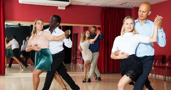 Drei Paare stehen in Tanzposition in der Tanzschule