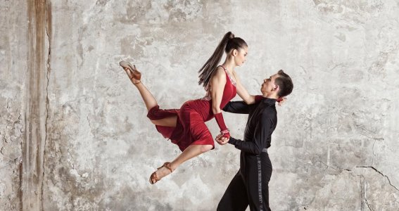 Eine weibliche Tänzerin posiert in einer Tanzbewegung in der Luft und stützt sich auf ihren Tanzpartner
