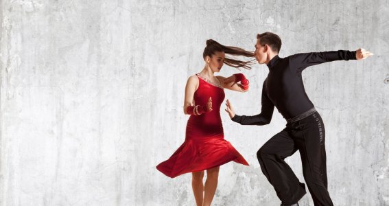 Ein professionelles Tanzpaar tanzt in vollem Schwung vor hellem Hintergrund