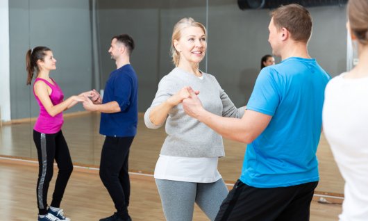 Zwei Tanzpaare tanzen in Sportkleidung in einem Raum mit einer Spiegelwand