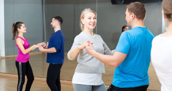 Zwei Tanzpaare tanzen in Sportkleidung in einem Raum mit einer Spiegelwand