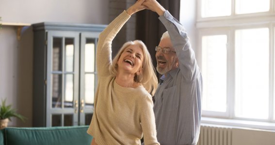 Ein älteres Paar tanzt im Wohnzimmer 