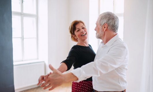 Zwei Senioren tanzen in einem hellen Wohnraum 
