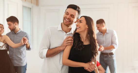Drei junge fröhliche Paare tanzen in einem Wohnraum