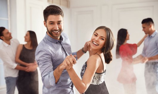 Drei junge Paare tanzen in einem Wohnraum