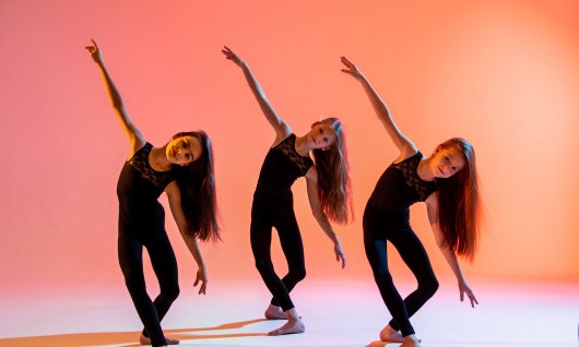 Drei Mädchen mit langen offenen Haaren beugen sich im Tanzschritt auf die Seite