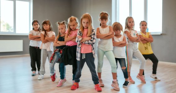 Eine Gruppe von kleinen Mädchen stehen im Dreieck und posieren im Street Dance Style