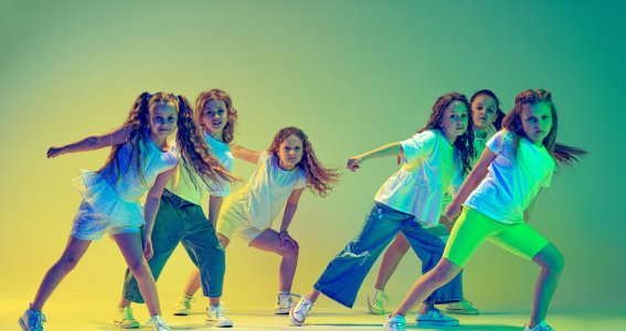 Eine Gruppe von Mädchen tanzt vor gelb-grünem Hintergrundf