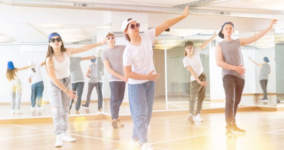 Fünf Jugendliche tanzen mit coolen Kappen und lässiger Kleidung im Tanzstudio