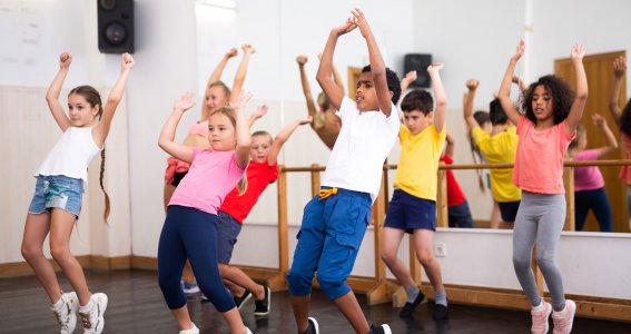 Eine Tanzgruppe von Kindern stehen auf den Zehenspitzen und tanzen Hip Hop