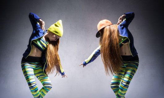 Zwei junge Frauen in gleicher lässiger Kleidung bieten sich ein Tanzduell in Hip Hop