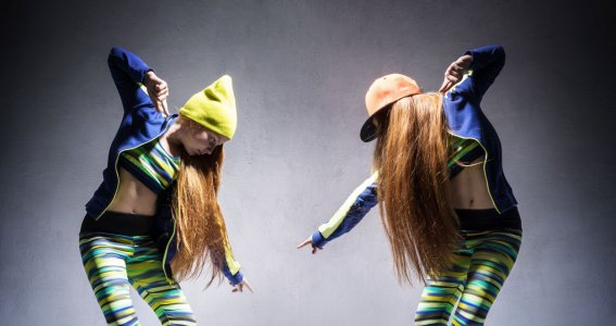 Zwei junge Frauen in gleicher lässiger Kleidung bieten sich ein Tanzduell in Hip Hop