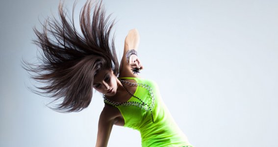 Eine junge Frau in lässiger Kleidung tanzt Hip Hop und posiert auf den Zehenspitzen
