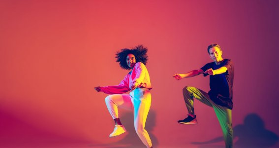 Zwei Jugendliche tanzen im Gleichschritt Hip Hop in gelb-rotem Licht