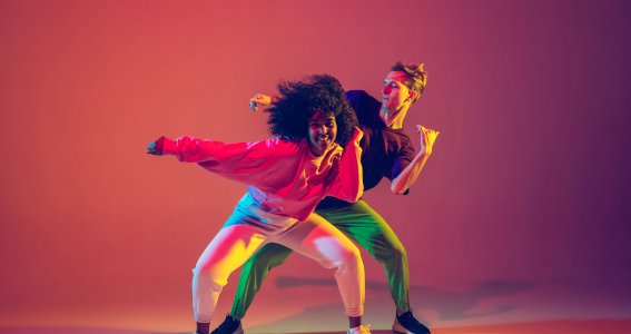 Zwei Jugendliche tanzen gemeinsam Hip Hop unter bunten Lichteffekten